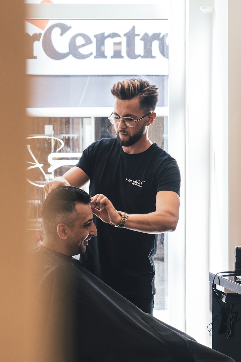 Barber styling a client's hair in a modern barbershop.