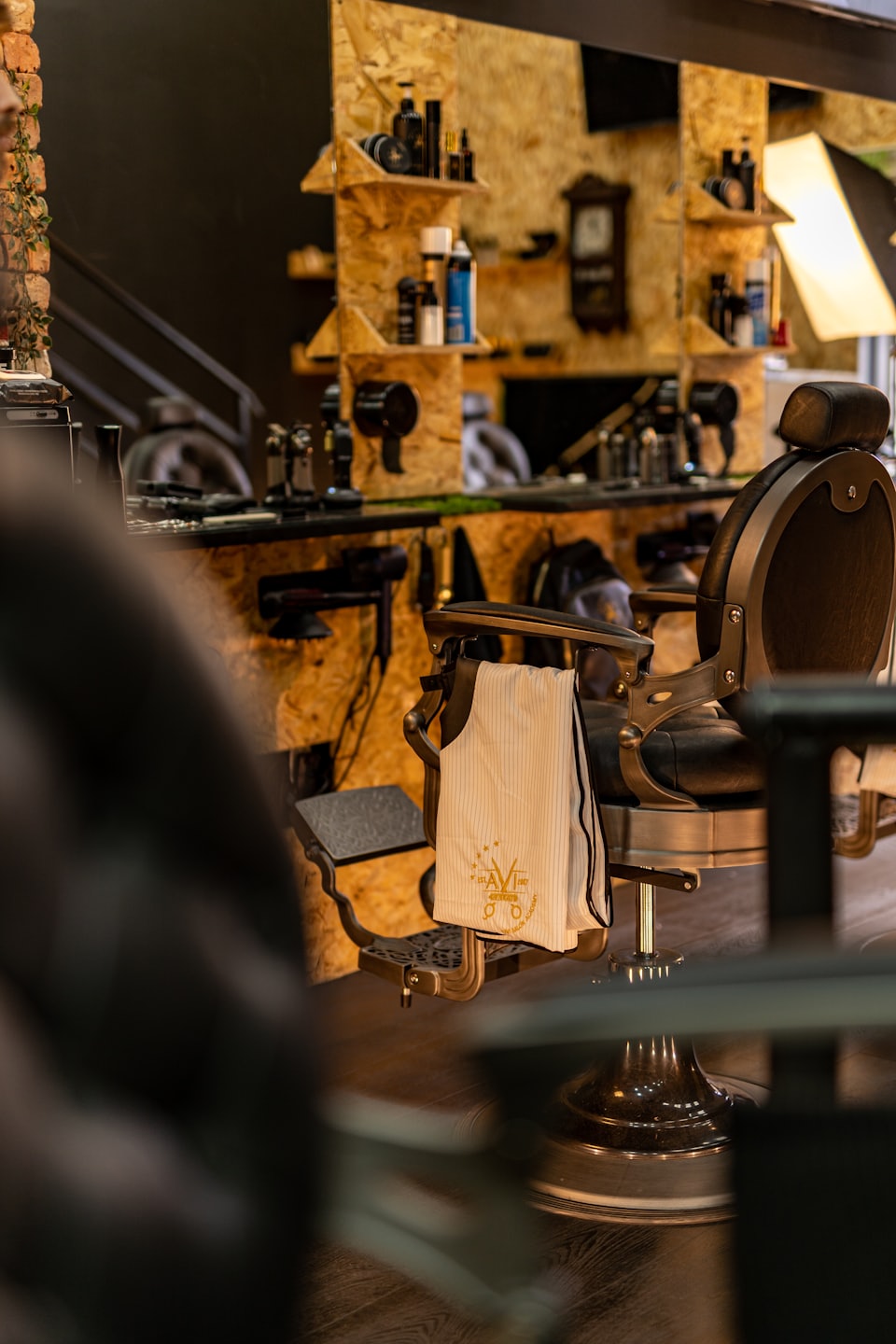 A black leather barber chair with a draped towel sits inside.